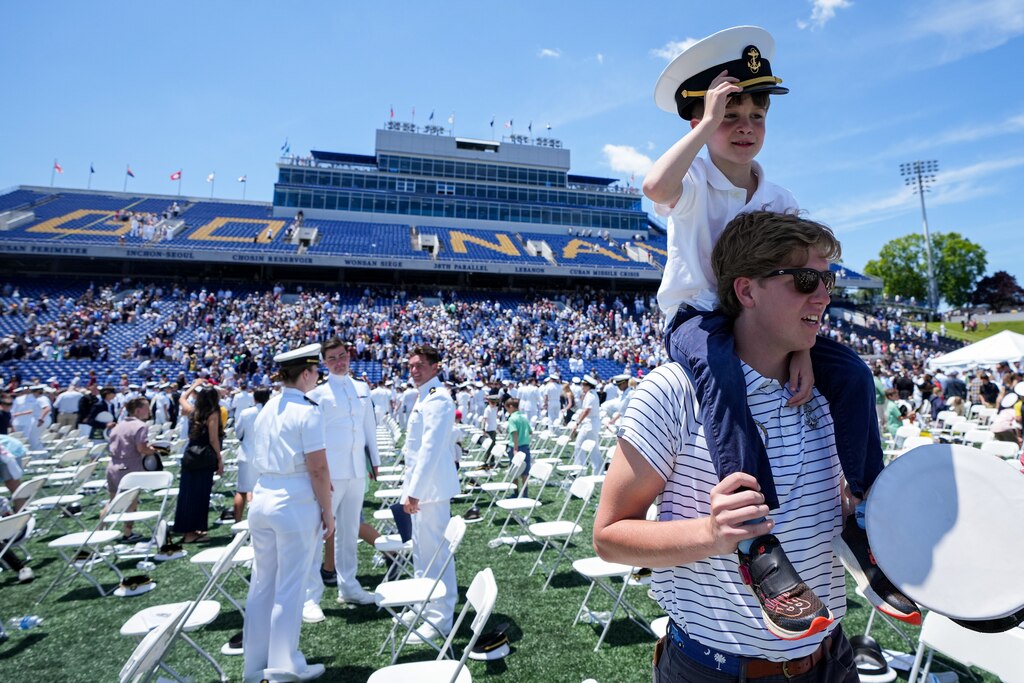 Sporting a former midshipman’s discarded cover, Robert Payton, 6, rides around on the shoulders of J.D. Patterson at the U.S. Naval Academy’s graduation ceremony at the Navy-Marine Corps Memorial Stadium on May 26, 2023. The graduating midshipmen are commissioned as either an ensign in the U.S. Navy or a 2nd Lieutenant in the U.S. Marine Corps.