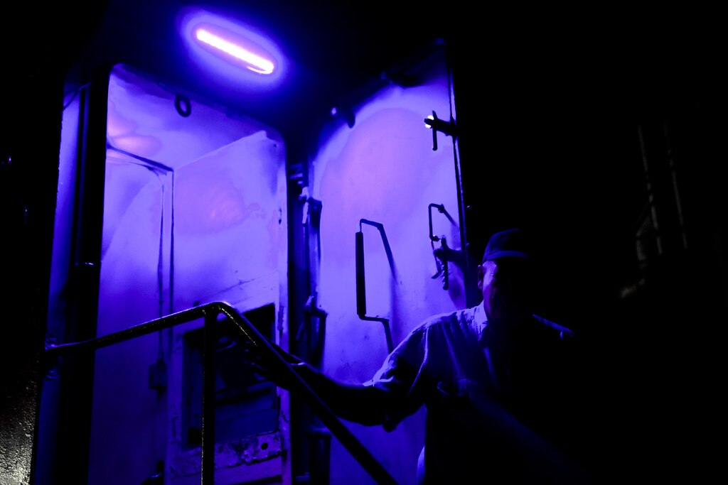 A staff member is illuminated by a purple light to guide the guests on a haunted tour of the SS John W. Brown in Baltimore on Friday, October 18, 2024.