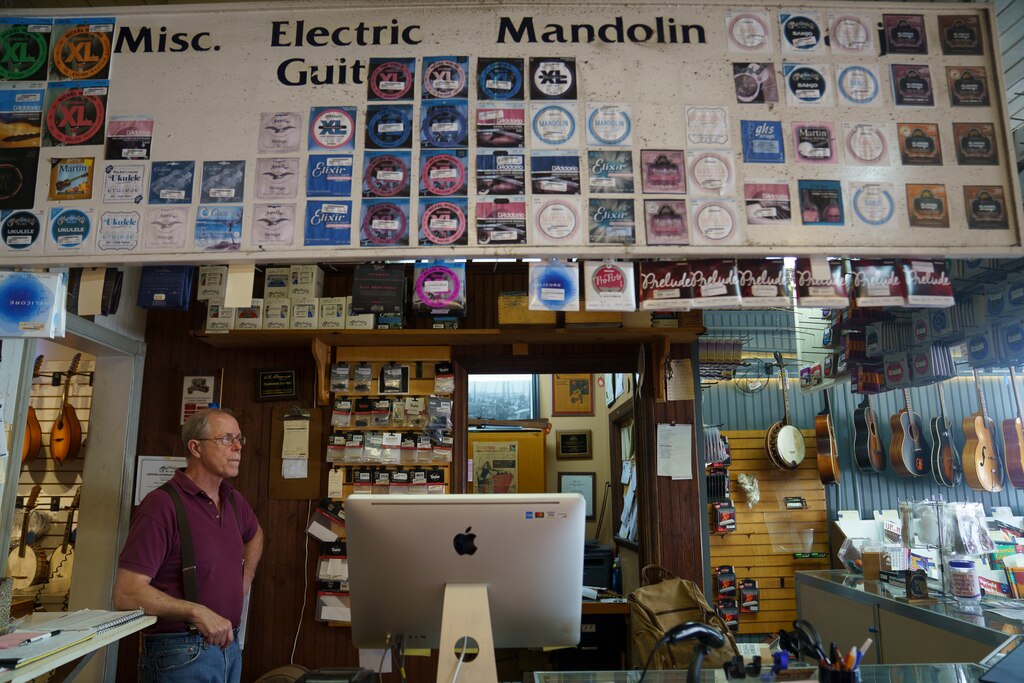 Bill Racine, a sales associate at the Appalachian Bluegrass Shoppe in Catonsville, Baltimore County, Md. mans the front desk on July 2, 2025.