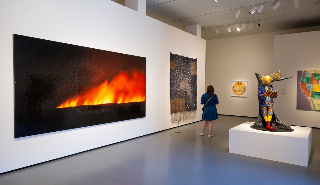 A Baltimore Museum of Art visitor observes the “Black Earth Rising” exhibit, including Teresita Fernández’s “Fire (America) 1” (left).