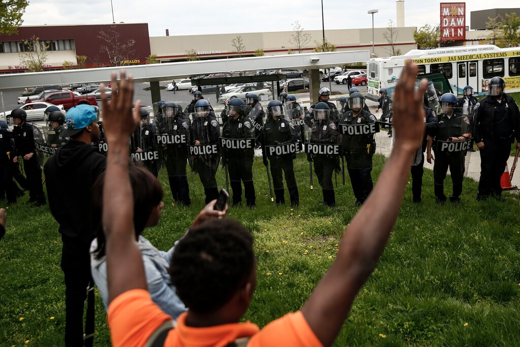 BALTIMORE, MD - APRIL 27: A protestors confronts Baltimore Police officers with his hands up near Mondawmin Mall, April 27, 2015 in Baltimore, Maryland. The funeral service for Freddie Gray, who died last week while in Baltimore Police custody, was held on Monday morning.
