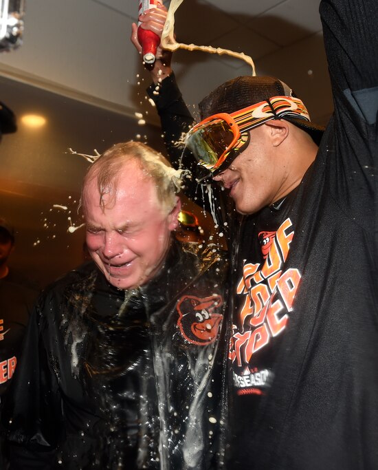 Baltimore Orioles manager Buck Showalter is doused with beer by Manny Machado in the visitors' clubhouse after the Orioles defeated the New York Yankees 5-2 in a baseball game to go to the playoffs , Sunday, Oct. 2, 2016, in New York.