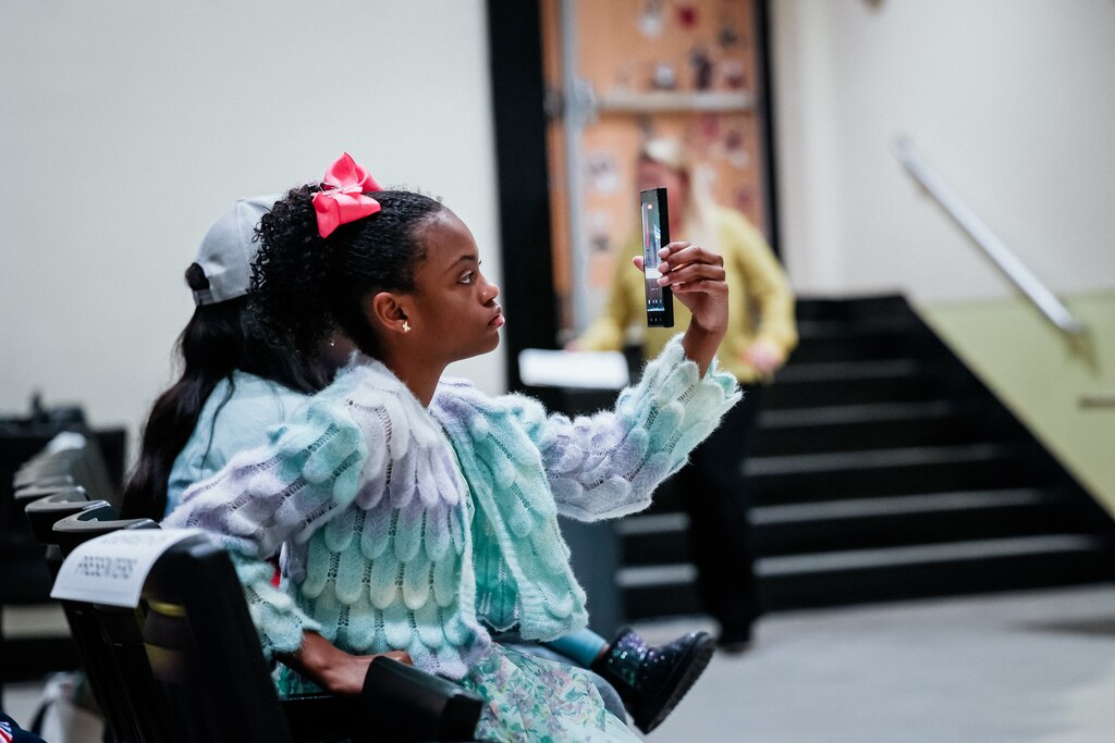 BALTIMORE, MD - May 28, 2025: Arielle Ross, 11, takes a video of her mother, Kim Ross, a District 8, Baltimore County Delegate, as she presents scholarship awards to seniors of Parkville High School at the senior award ceremony on May 28, 2025.