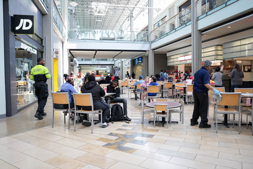 Ofc. Brian Onwezi, left, walks through the food court seating area inside the Mall in Columbia in Columbia, Md. on Monday, May 19, 2025.