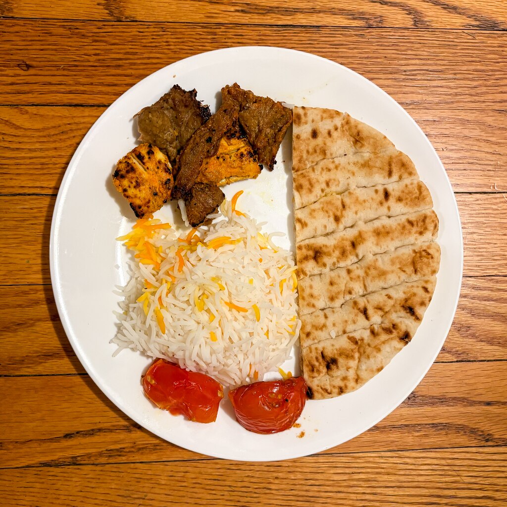 A plate of rice, pita, grilled meat and tomato from Vellagio Cafe.