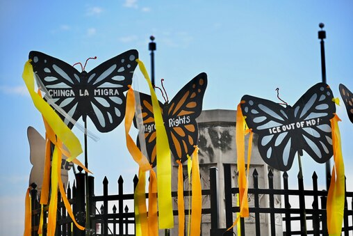 Signs decorate a fence ahead of the March for Migrant Justice at Columbus Park in Baltimore on Thursday, May 1, 2025.