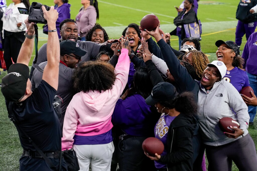 After completing football drills, women put their hands together and cheer during A Purple Evening, the Baltimore Ravens’s annual women’s event, at M&T Bank Stadium in Baltimore on Monday, October 14, 2024.