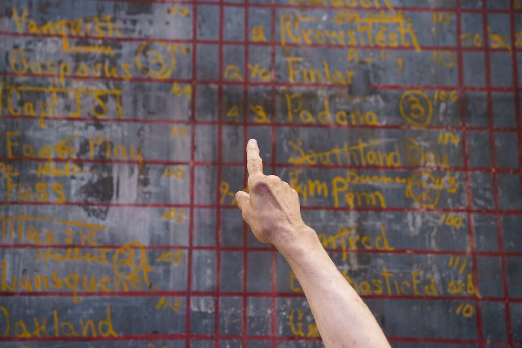 Bob Romiti, owner of Squire’s Italian Restaurant and Catering in Dundalk, Md., points out the jockeys’ weights listed on the blackboard. June 30, 2025.