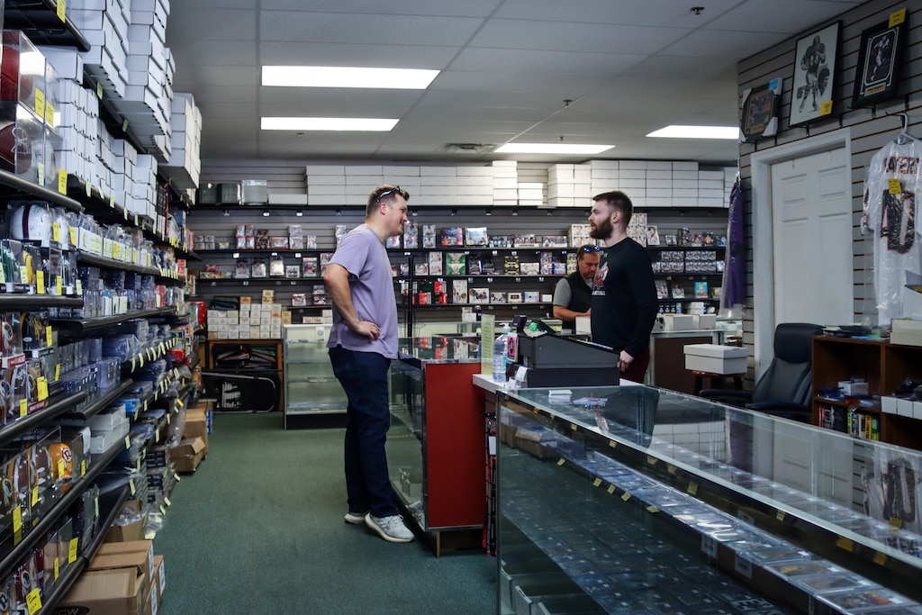 Sports Cards Heroes owner Steven Jordan, 27, talks to Michael Vanover, 28, about the upcoming Baltimore Ravens match against the Washington Commanders.