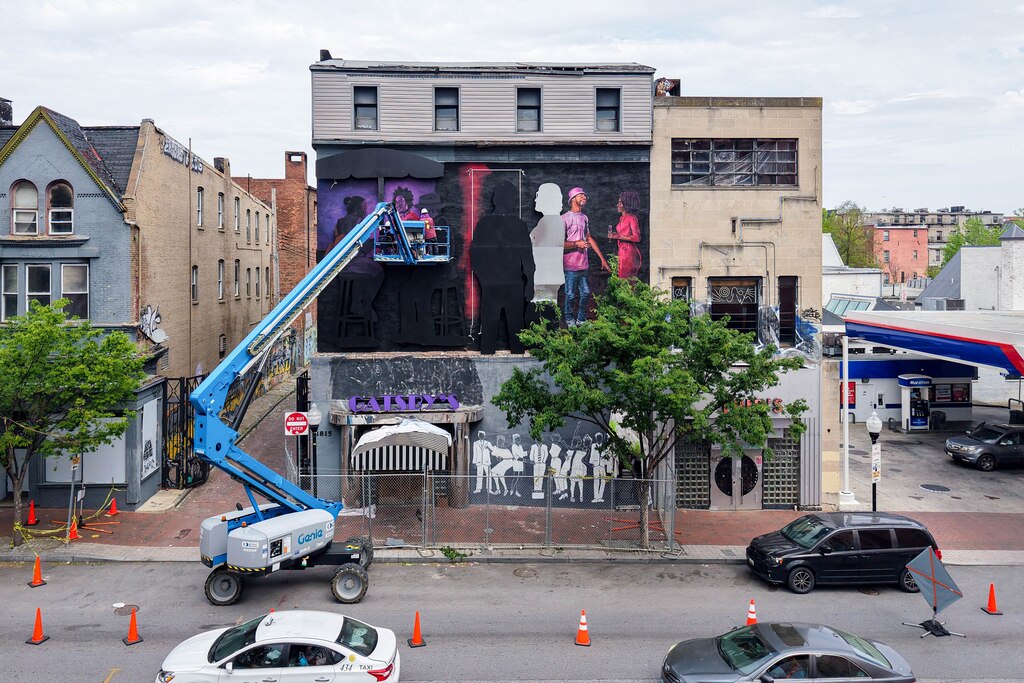 Artist Tony Shore, with assistance from street artist Gaia to his left, works on his installation, "Aurora," outside of the old Gatsby's nightclub in the Station North neighborhood of Baltimore, Md. on Friday, April 25, 2025.