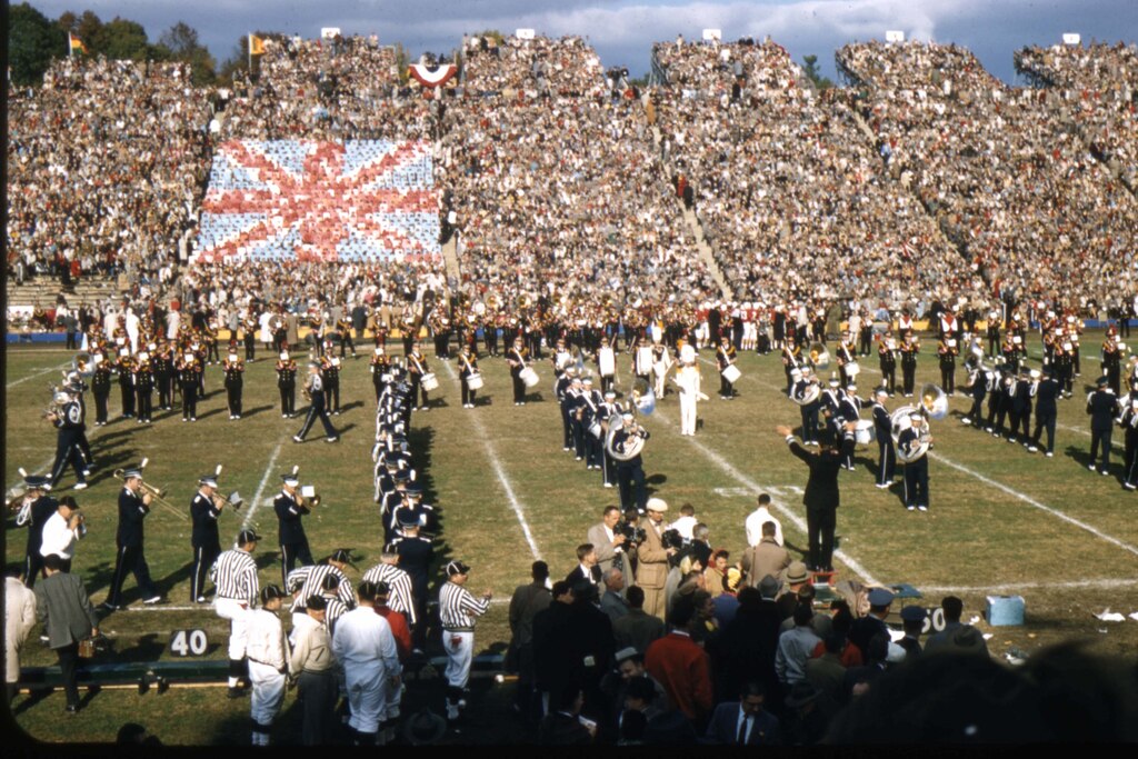 The University of Maryland marching band in formation on the field with the card section forming the Union Jack flag in the background during the Queen's Game at the University of Maryland on October 19, 1957. Courtesy of University of Maryland Archives.
