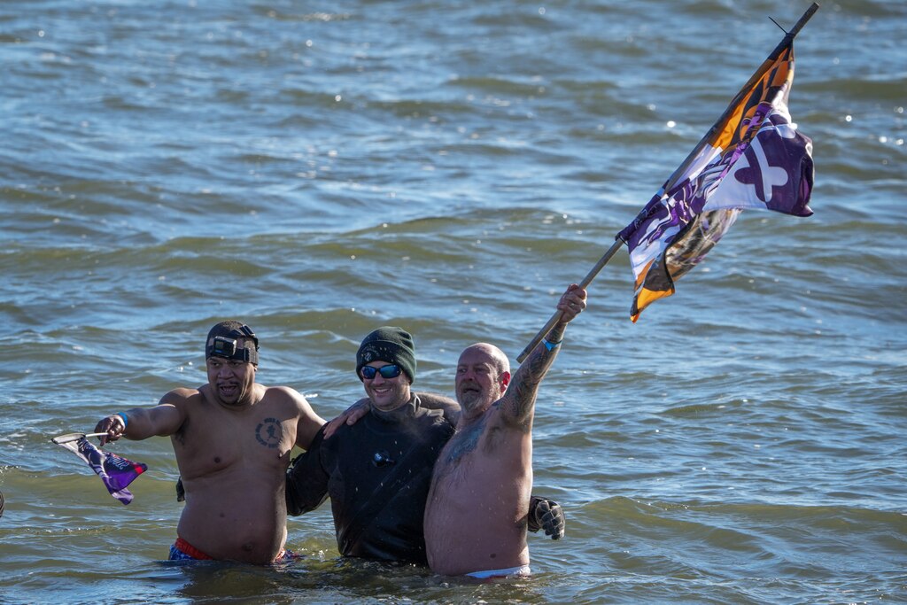 Two plungers wave their flags while embracing a member of the Dive Team at the Polar Bear Plunge on 2/4/23 at Sandy Point State Park. The event, now in its 27th year, has raised more than $3.4 million for Special Olympics Maryland this year.