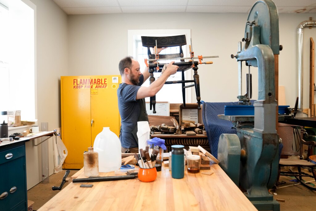 Phillip Kerrigan carries a broken chair through his furniture restoration workshop in Baltimore, Md. on Wednesday, July 3, 2025.
