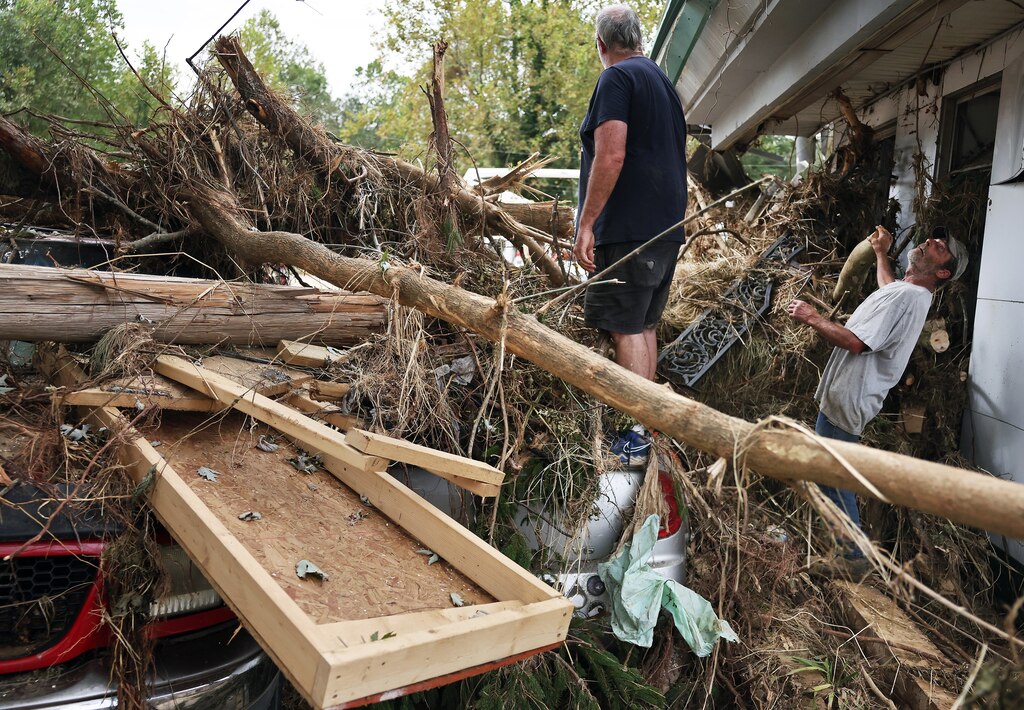 ASHEVILLE, NORTH CAROLINA - OCTOBER 04: People clear flood debris from Monteath's Auto Service in the aftermath of Hurricane Helene flooding along the Swannanoa River on October 4, 2024 in Asheville, North Carolina. At least 215 people were killed in six states in the wake of the powerful hurricane which made landfall as a Category 4. President Joe Biden ordered the deployment of 1,000 active duty U.S. soldiers to assist with storm relief efforts in what is now the deadliest U.S. mainland hurricane since Hurricane Katrina. (Photo by Mario Tama/Getty Images)