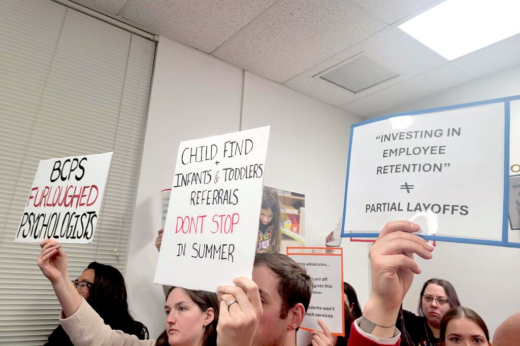 Baltimore County educators hold signs in protest of the reclassification of school psychologists and counselors going from 12-month to 10-month employees during a March 25, 2025, school board meeting in Towson.
