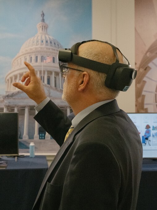 A man wearing a headset device holds up his fingers at the Hopkins on the Hill research showcase in the Rayburn House Office Building in Washington, D.C., on June 12, 2025.