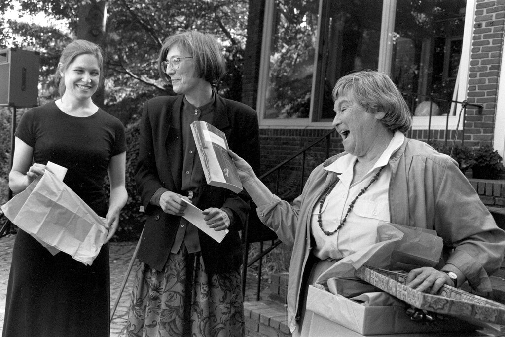 At the retirement party for Eva Brann, the dean reads with surprise at a galley copy of her newest book, The Past-Present, delivered by tutor Pamela Kraus and designer Adrienne Rogers.