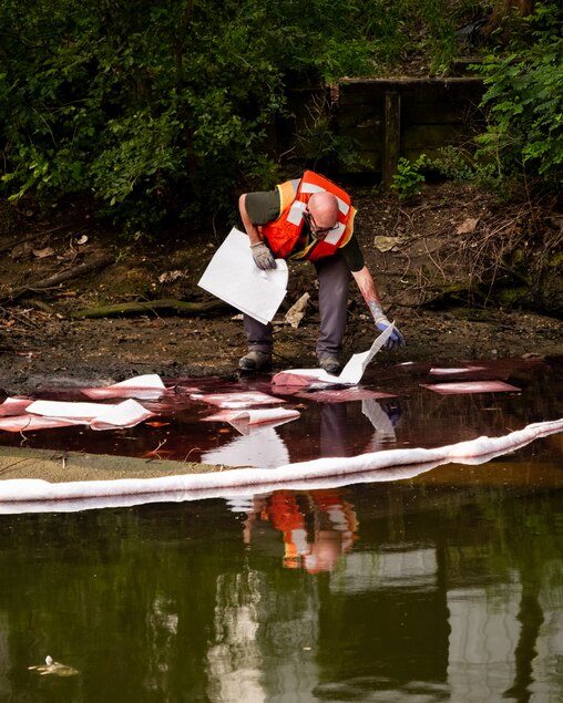 Crews work to lay down absorbent sheets to clean up an oil spill at an inlet at S. Caroline Street and Lancaster Street, near the Crossroads Charter School, on Thursday, June 5, 2025, after an oil spill nearby on Wednesday.