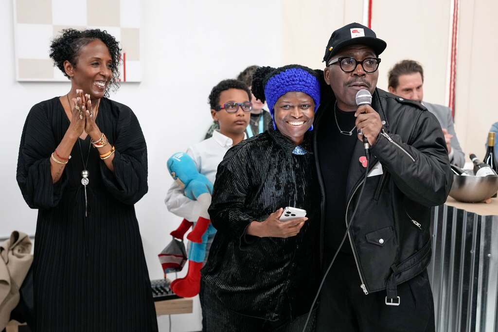 Inviting Light lead curator Derrick Adams, right, embraces artist Zoë Charlton as he gives remarks during the opening night for her “Third Watch” installation at North Avenue Market inside Currency Studio in Baltimore, Md. on Friday, March 28, 2025.