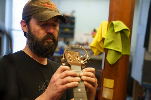 Nick Trossbach, a repair technician, restrings a guitar at the Appalachian Bluegrass Shoppe in Catonsville, Baltimore County, Md. on July 2, 2025.