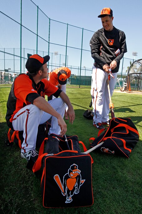 Baltimore Orioles' J.J. Hardy, left, talks with Manny Machado, right, while waiting to take batting practice during the team's first full squad workout of baseball spring training in Sarasota, Fla., Wednesday, Feb. 19, 2014.
