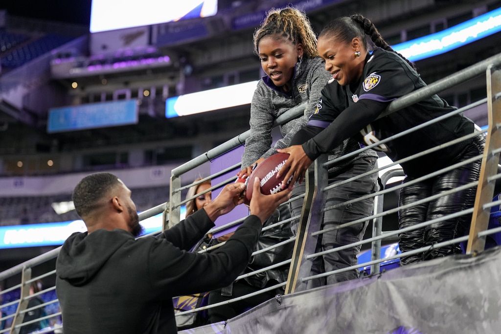Baltimore Ravens linebacker Josh Ross signs a football for two fans during A Purple Evening, the Baltimore Ravens’s annual women’s event, at M&T Bank Stadium in Baltimore on Monday, October 14, 2024.