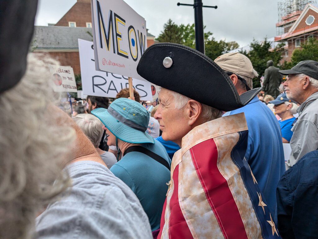 Baird Straughn of Annapolis listens as news of a political assassination in Minnesota is read to the crowd at the No Kings Rally at the State House Saturday morning.