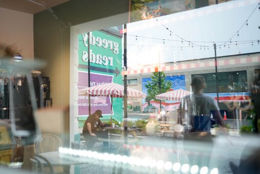 The outdoor seating area is reflected on the dessert display case inside Doppio Pasticceria in the Remington neighborhood of Baltimore, Md. on Tuesday, May 27, 2025.