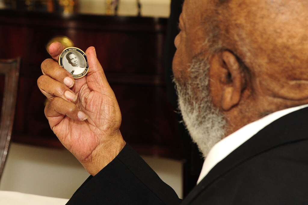 Retired Lt. Cmdr. Wesley Brown reflects upon his challenge coin that displays his U.S. Naval Academy photo while at the historic Tingey House at the Washington Navy Yard for a luncheon with the Chief of Naval Operations. Brown was the first African-American to graduate from the U.S. Naval Academy, June 3, 1949.