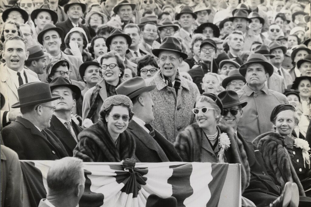 Queen Elizabeth II smiles as she sits in the stands at a football game between the University of Maryland and the University of North Carolina, October 19, 1957. In her row, from left to right: University of Maryland President Wilson Elkins, the Queen, Governor Theodore McKeldin, Mrs. Dorothy Elkins, and Prince Philip, Duke of Edinburgh. Courtesy of University of Maryland Archives.