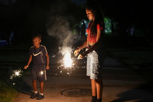 Bryx Johnson, 5, and Riley Johnson, 14, light up sparklers at Cherry Hill, Baltimore on July 4, 2025.