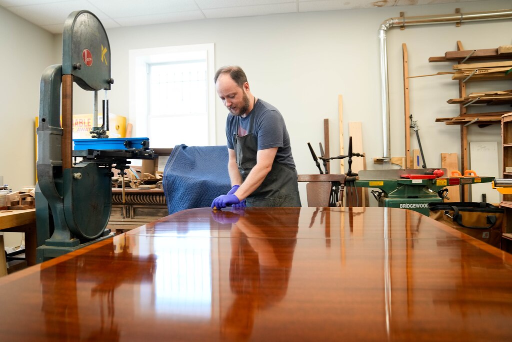 Phillip Kerrigan French polishes a customer’s table in his furniture restoration workshop in Baltimore, Md. on Wednesday, July 3, 2025.