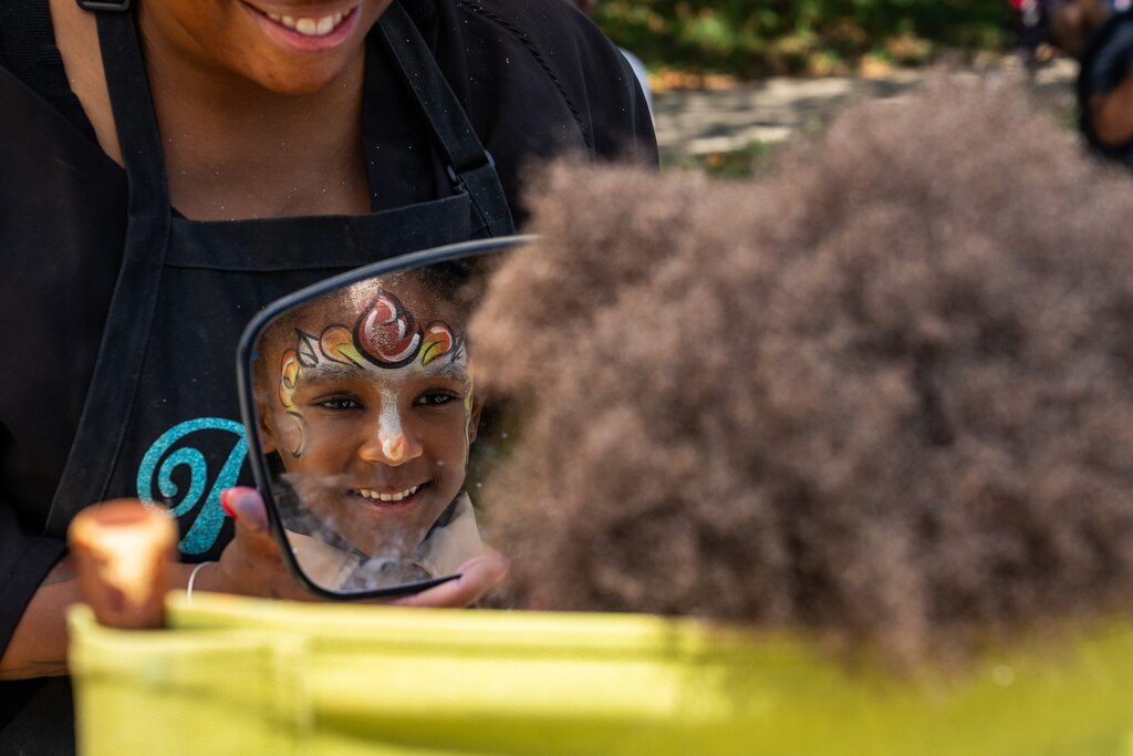 Layla, 6, smiles into a handheld mirror as she sees her unicorn face paint.