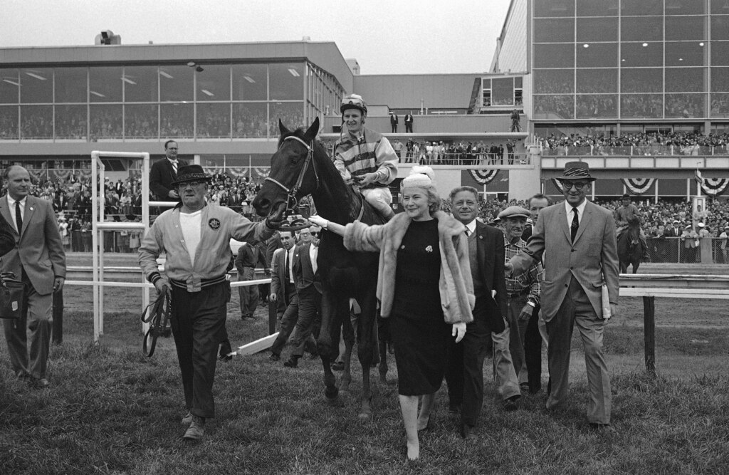 Mrs. Katherine Price leads her Carry Back to the winner's circle after his victory in the 85th Preakness at Pimlico in Baltimore, Maryland on May 20, 1961. Jockey John Sellers, who also rode Carry Back to his Kentucky Derby triumph, is aboard. Jack Price, trainer and the owner's husband, is at right beside the horse.