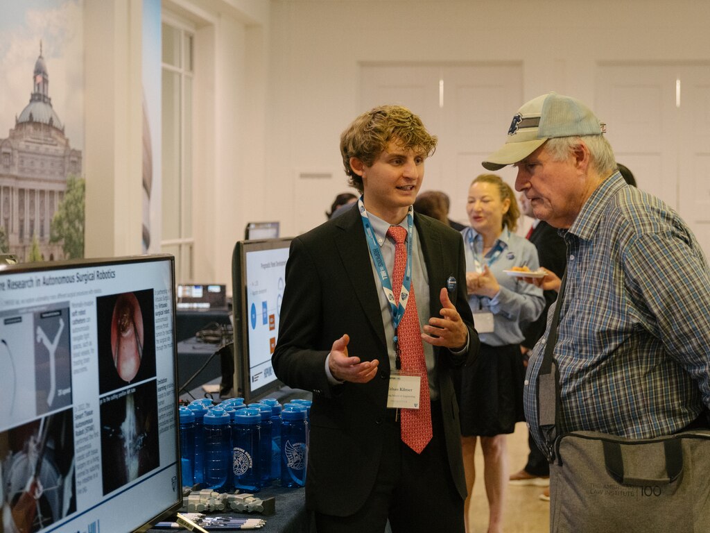 Ethan Kilmer explains the Autonomous System for Tumor Reception (ASTR) device to an attendee, at the Hopkins on the Hill research showcase in the Rayburn House Office Building in Washington, D.C., on June 12, 2025.