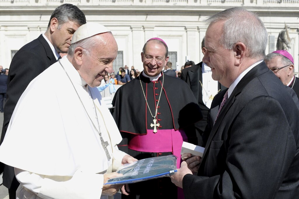 Bill McCarthy, right, executive director of Catholic Charities, gives Pope Francis an apron embroidered with the words "Our Daily Bread" in 2016 in St. Peter's Square in Rome. Standing between them is Archbishop William E. Lori of the Archdiocese of Baltimore.