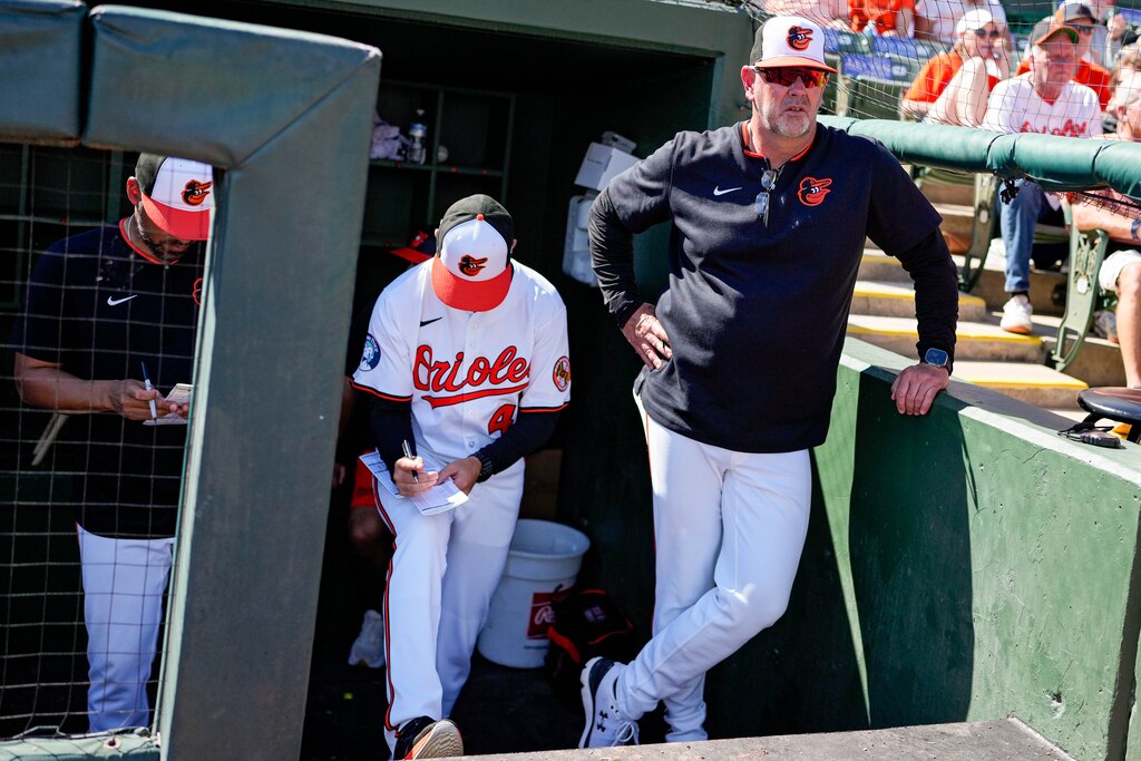 Baltimore Orioles manager Brandon Hyde (18) stands in the dugout to watch his team play a Grapefruit League game against the Detroit Tigers at Ed Smith Stadium in Sarasota, Fla. on Tuesday, Feb. 25, 2025.