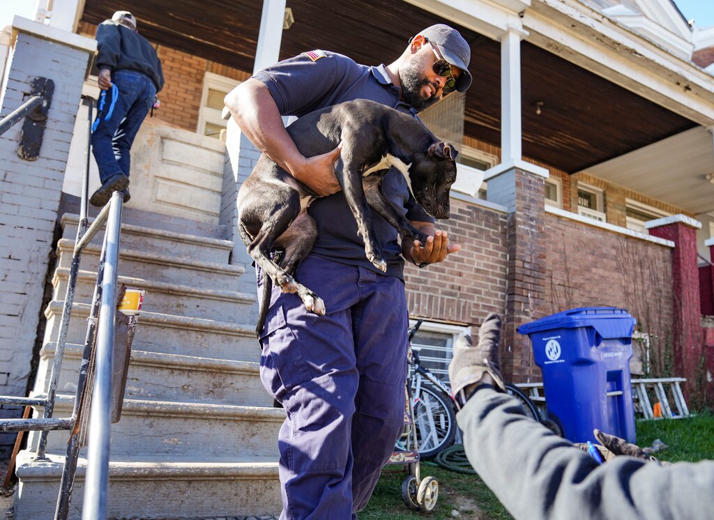Man hand off dog to another man.