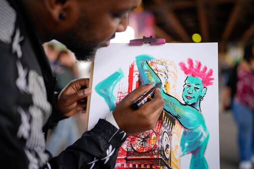 Artist Logic Thompson works on a collaborative painting project in the middle of the artisan market beneath the Jones Falls Expressway (JFX) at Artscape in downtown Baltimore, Md. on Saturday, May 24, 2025.
