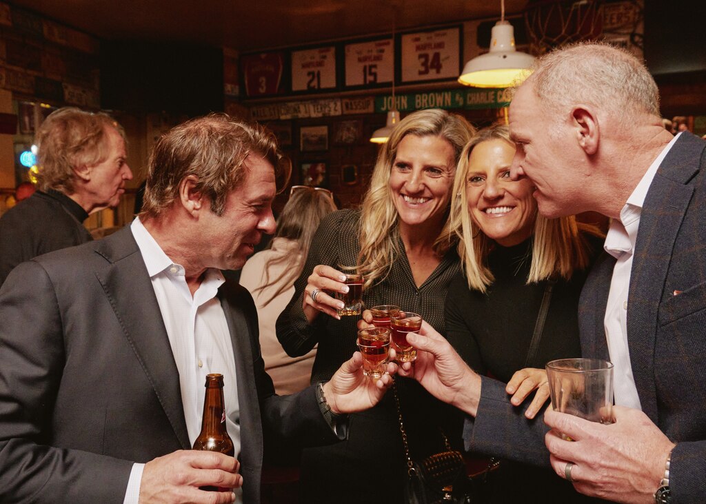 Brooke and Colby Carrier, center, former bartenders at RJ Bentleys, take shots with Jon Brothers, left, and Jason Carrier, right, to honor Brown.