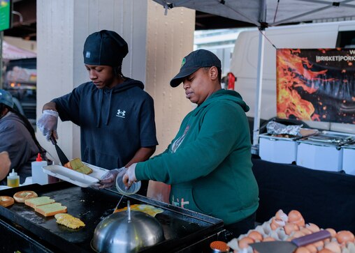 Chef Sam Scott, right, cooks at her Soul Smoked BBQ stand at the Baltimore Farmer’s Market opening day in downtown Baltimore, MD on April 13, 2025. Scott plans to open a stand in the Broadway Market this summer.