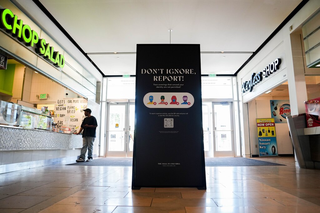 Signage reading “don’t ignore, report” and facial covering policies at the Mall in Columbia in Columbia, Md. on Monday, May 19, 2025.