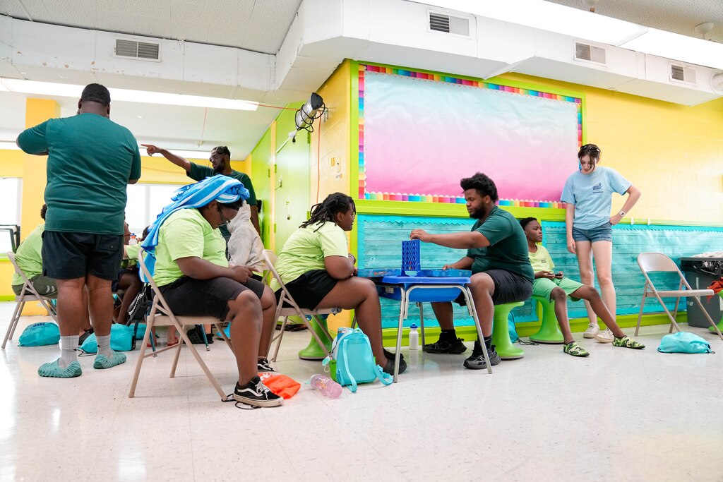Camp counselor Isaiah Magruder, center right, plays Connect Four with a camper in his group during one of Camp St. Vincent’s youth activity sessions at Patterson Park in Baltimore, Md. on Wednesday, June 25, 2025.