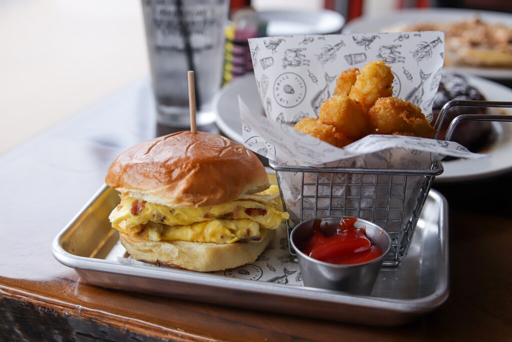 A bacon, egg and cheese omelet sandwich with a side of tater tots at Lib's Grill.