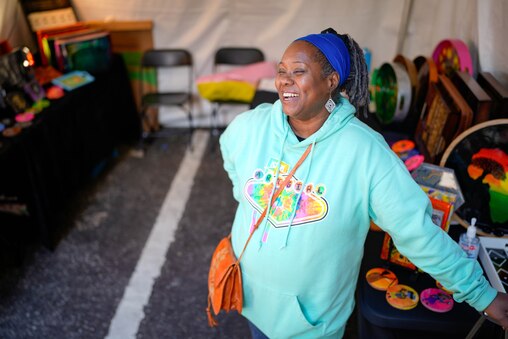 Monique Downs, owner of MADXpressions, laughs during an interview inside her booth at the artisan market beneath the Jones Falls Expressway (JFX) at Artscape in downtown Baltimore, Md. on Saturday, May 24, 2025.