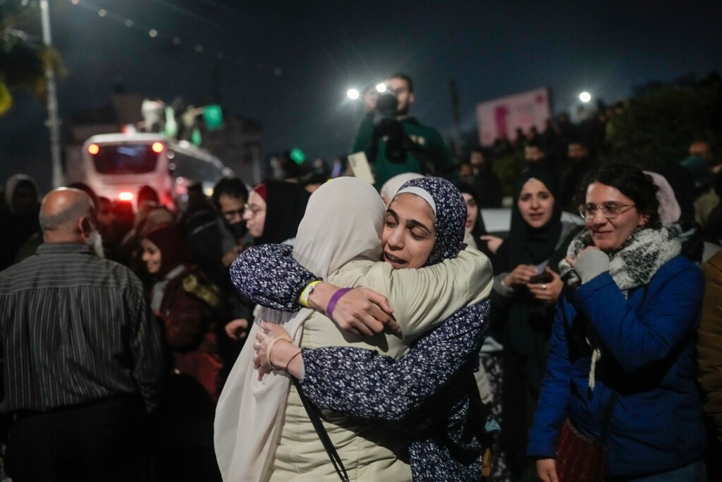 A female Palestinian hostage, center left, is greeted after disembarking from a bus following her release from an Israeli prison, in the West Bank city of Beitunia, early Monday, Jan. 20, 2025.