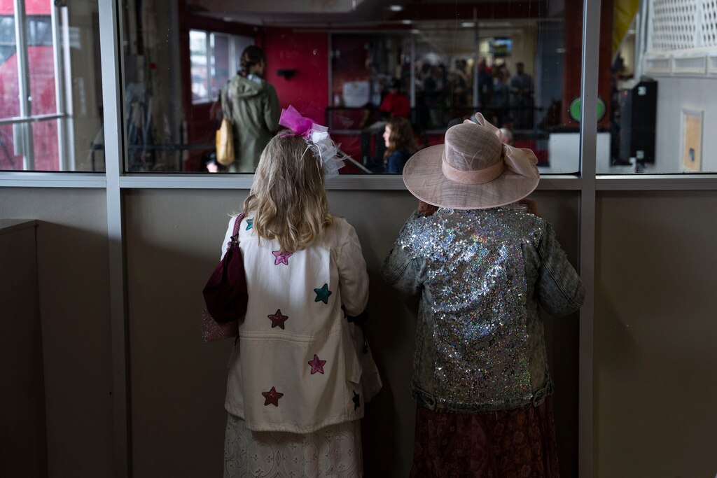 Two ladies peek over the edge into the paddock at Pimlico on May 18, 2024.
