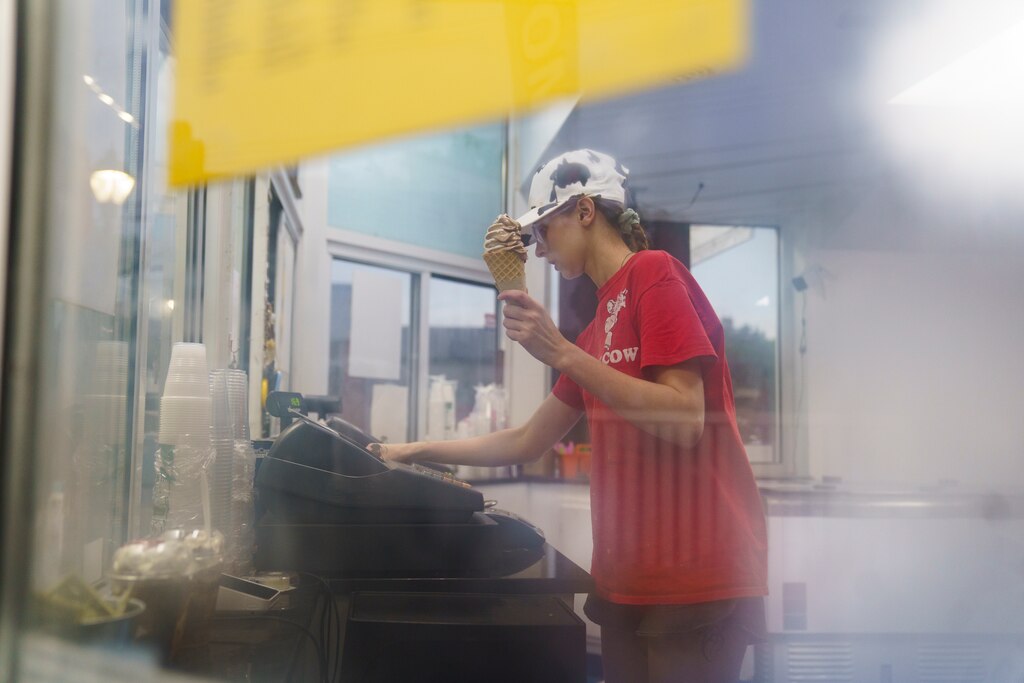 Grace Smith checks a customer out at the register while handing them their order at The Cow in Reistertown, Md. on July 1, 2025.