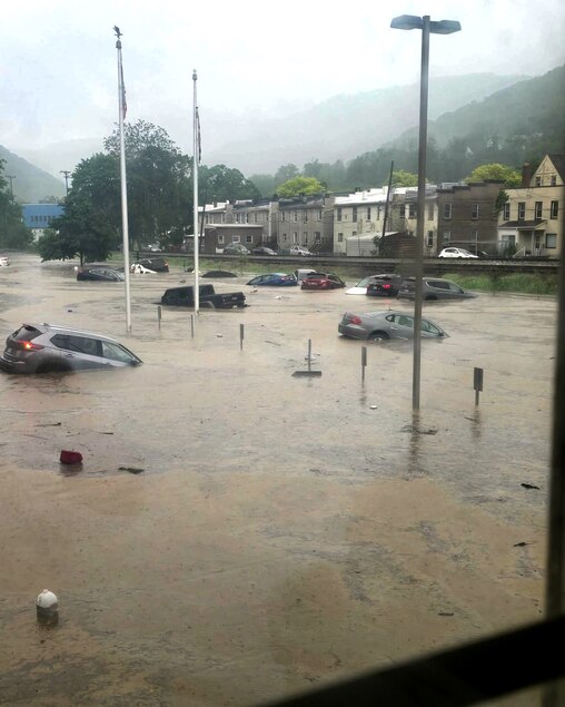 Cars belonging to teachers cars float in the parking lot of Westport Elementary, the floodwaters causing the car lights to flash.