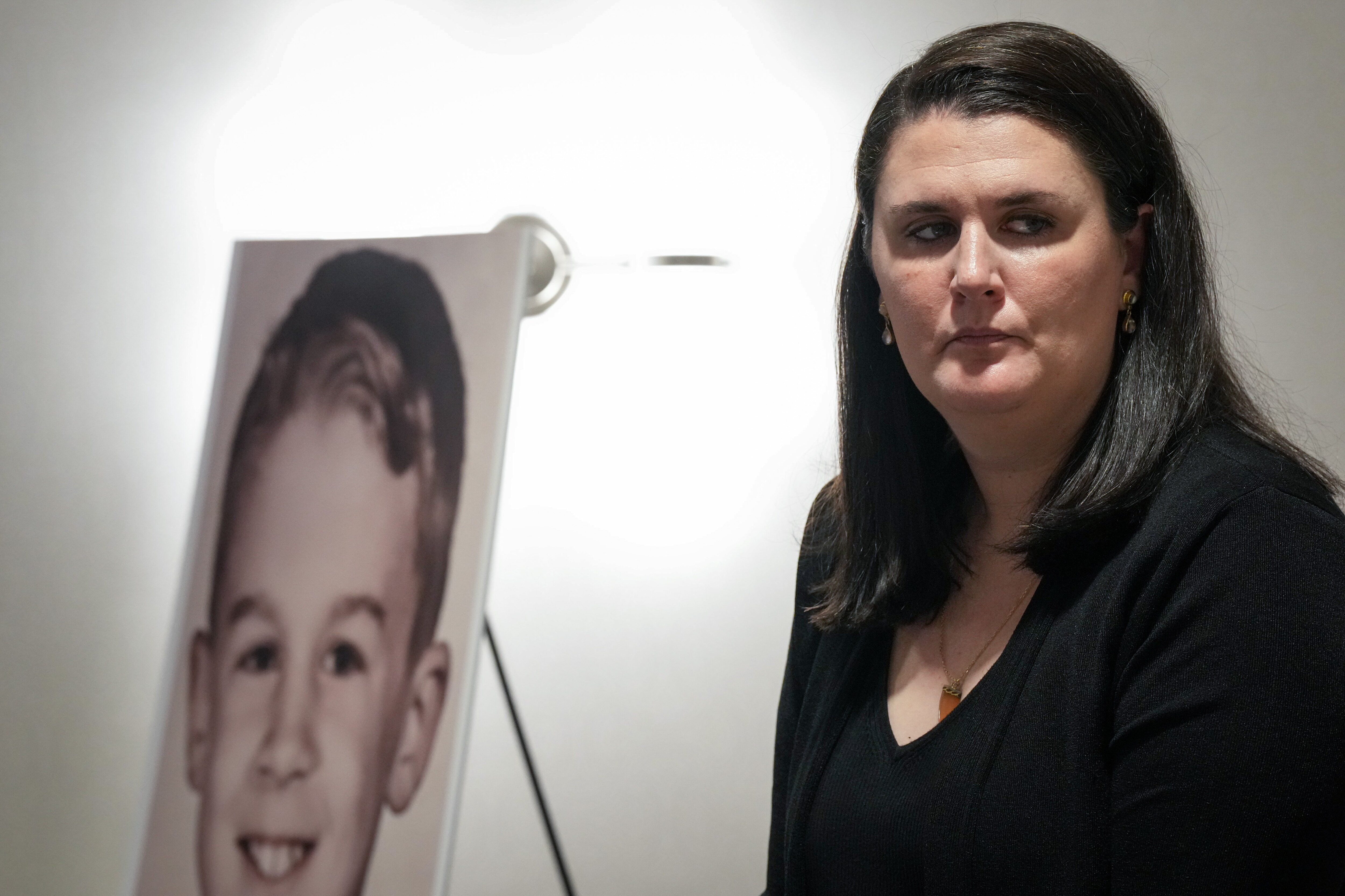 Flannery Gallagher sits in front of a childhood photo of her deceased father, Frank X. Gallagher Jr., during a press conference announcing a lawsuit against St. Mary’s Seminary and the Archdiocese of Baltimore on Tuesday, June 27, 2023. Flannery and Liam Gallagher, the children of Frank X. Gallagher Jr., say that after the abuse their father “experienced extreme emotional distress” and began experimenting with drugs and engaging in compulsive and risky sexual encounters.